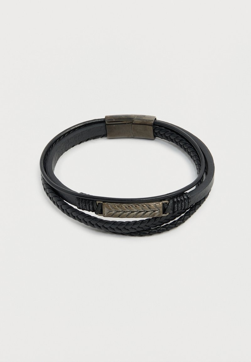 Bracelet en cuir noir enroulé avec détail tressé et fermoir en métal, muni d'une plaque métallique rectangulaire gravée d'une feuille.