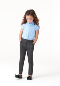 Cămașă bleu deschis cu mâneci scurte și nasturi pe față, asortată cu pantaloni skinny gri închis și mocasini negri din piele lucioasă.