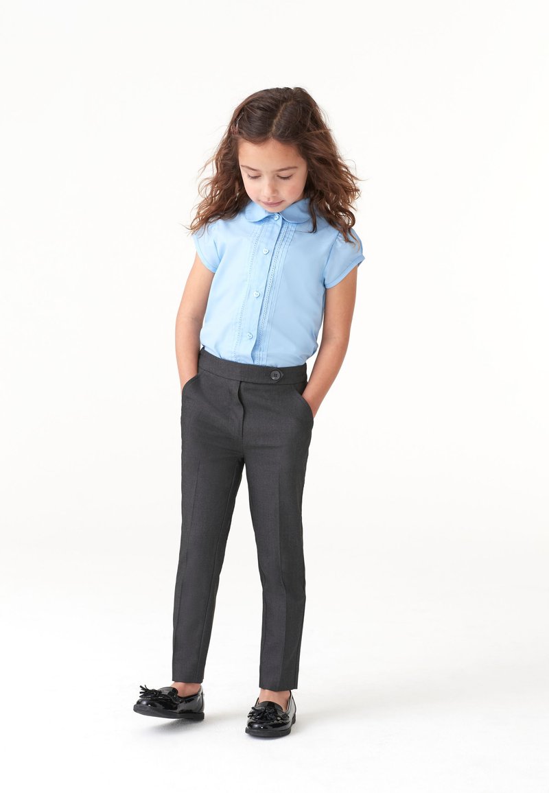 Cămașă bleu deschis cu mâneci scurte și nasturi pe față, asortată cu pantaloni skinny gri închis și mocasini negri din piele lucioasă.