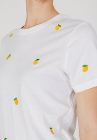 Witte katoenen t-shirt met korte mouwen, voorzien van verspreide gele citroen borduursels met groene bladeren. Glad textuur, ronde halsontwerp.