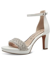 Hvide højhælede sandaler med en tekstureret metalrem, ankelbuckle og glat buet sål. Har en vævet detalje foran.