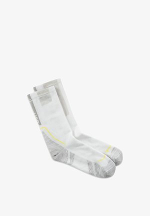 Par de calcetines blancos hasta el tobillo con zonas grises en el talón y la punta, líneas de acento amarillas y patrones grises sutiles sobre un fondo blanco liso.