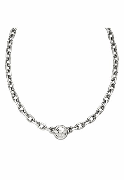 Collar de cadena de metal plateado con eslabones ovalados y un colgante circular con un diseño de águila en el centro. Acabado liso y pulido.