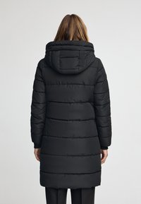 Svart puffjacka med ett quiltat mönster, med stor huva, långa ärmar och en medellång passform, tillverkad av ett slätt, matt material.