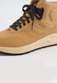 Hnědé nepromokavé vysoké tenisky s texturovaným síťovým svrškem, černými tkaničkami a pevným gumovým podešví navrženým pro trakci a odolnost.