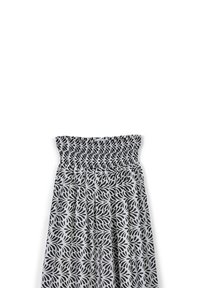 Abito smockato nero e bianco con un motivo floreale, caratterizzato da un corpetto arricciato e una gonna plissettata. Tessuto leggero con una texture liscia.