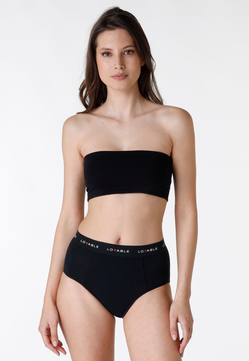 Top nero a tubo in tessuto liscio, abbinato a biancheria intima nera a vita alta con cintura elastica con logo. Design semplice e aderente.