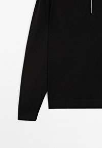 Černý top s dlouhým rukávem vyrobený z měkké tkaniny, s vysokým krkem na zip, jednoduchý design a vroubkované manžety a lem.