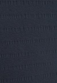 Mörk marinblå ribbad tyg med en texturerad mönster av vertikala linjer. Mjuk textur som är lämplig för olika klädesapplikationer.