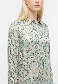 Langærmet skjorte i lys grøn med blomster- og paisley-mønstre. Fremstillet af blødt stof, med en knapkrave og en subtil glans.