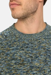 Maglione lavorato a maglia in tonalità blu e giallo. Colletto a coste. Tessuto morbido e texture con un motivo misto. Primo piano dell'area del collo e delle spalle.