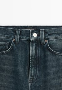 Mörka jeans i denim har en klassisk femficksdesign med en silverknapp och kontrasterande sömmar vid midjan och fickorna.