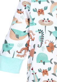 Witte stof voor kinderen met kleurrijke glimlachende zeewezens, waaronder walvissen, haaien, zeepaardjes, krabben en octopussen in blauwe en oranje tinten.