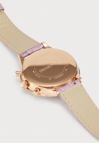 Orologio in acciaio inox rosa oro con cinturino in satin rosa. Presenta una cassa rotonda, retro inciso e tre pulsanti laterali per la funzionalità.