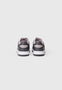 Sneakers Nike z ciemnoszarym cholewką i jasnoszarymi akcentami, z wyściełanym kołnierzem i białą podeszwą środkową. Teksturowana podeszwa zewnętrzna zapewniająca przyczepność.