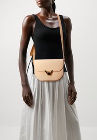 Borsa a tracolla in pelle color pesco con chiusura a patta e hardware dorato, caratterizzata da una texture liscia e un design minimalista. Inclusa una tracolla regolabile.