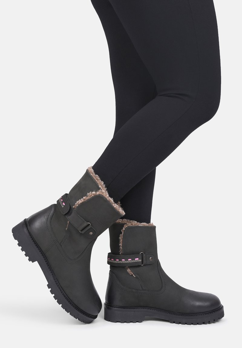 Czarne botki z ekoskóry z futrzanym wykończeniem, paskiem przy kostce i teksturowaną gumową podeszwą. Charakteryzują się płaskim obcasem i przeszyciami.