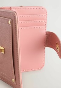 Portofel compact din piele texturată de culoare mauve, cu interior roz deschis, având sloturi pentru carduri și accente aurii. Deschiderea dezvăluie designul interior.