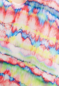 Blouse à col en V en tissu fluide avec des rayures ondulantes abstraites multicolores dans les tons rouge, bleu, vert et jaune. Texture légère et douce.