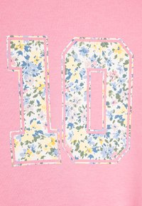Pink sweatshirt featuring the number "10" in floral fabric with blue, yellow, green, and pink accents, outlined with a contrasting stitch.