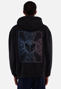 Zwarte hoodie met een groot, kleurrijk geometrisch ontwerp op de achterkant, waarin golven, vlammen en een oogsymbool zijn verwerkt.