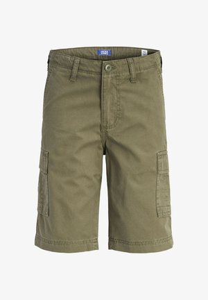 Ragazzo con maglietta blu navy con piccolo logo bianco, pantaloncini cargo kaki, calzini bianchi e scarpe da ginnastica bianche, guarda a sinistra.