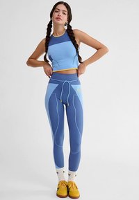 Niebieski sportowy krótki top i legginsy w różnych odcieniach niebieskiego, z elastycznym materiałem, prążkowaną fakturą i subtelnymi żółtymi akcentami.