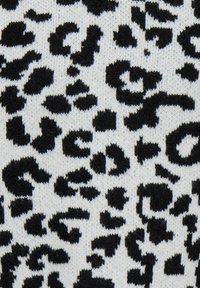 Megztas audinys su juodu leopardų raštu ant balto fondo, pabrėžiantis įvairias dėmių formas ir tekstūras.