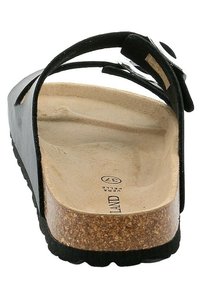 Infradito neri con una suola in sughero, caratterizzati da una sola cinghia e una superficie texturizzata. Suola piatta con una leggera contropendenza e dettaglio della fibbia regolabile.