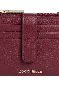 Portafoglio in pelle bordeaux con finitura testurizzata, con una fascia centrale e branding dorato sul fronte. Presenta più scomparti per carte e chiusura con zip.