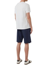 T-shirt blanc à manches courtes associé à un short bleu marine. La tenue présente une coupe décontractée et un design simple sans motifs visibles.