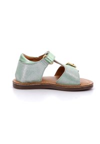 Sandalia de cuero verde menta con punta abierta, correa en el tobillo y detalle de hebilla dorada. Suela plana y acabado metálico texturizado.