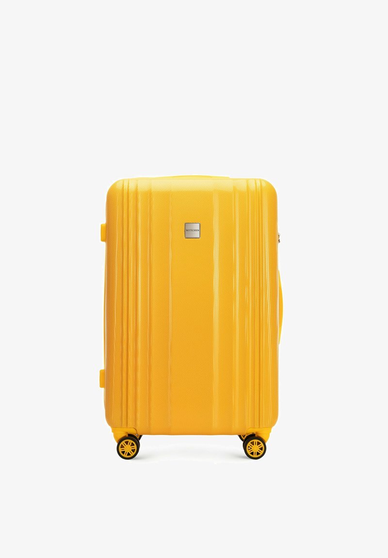 Gele harde koffer met een gestructureerd oppervlak, verticale groeven, een stevige handgreep en vier roterende wielen voor gemakkelijke mobiliteit.