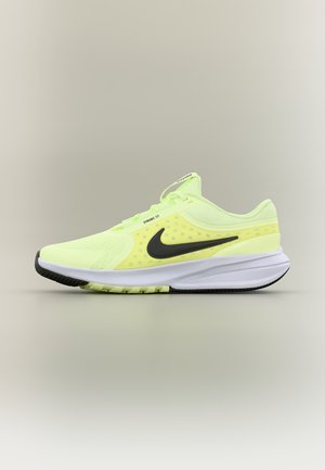 Zapatilla de running Nike de color amarillo brillante con logo swoosh negro y suela blanca, mostrada de perfil sobre fondo neutro.