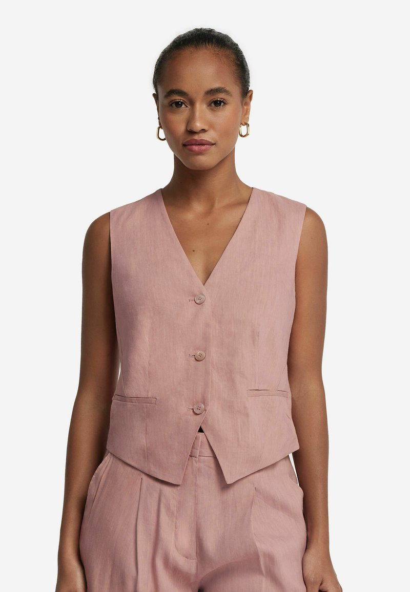 Gilet sans manches rose clair avec un décolleté en V, cinq boutons et deux poches avant. Fabriqué en tissu doux avec une texture lisse.