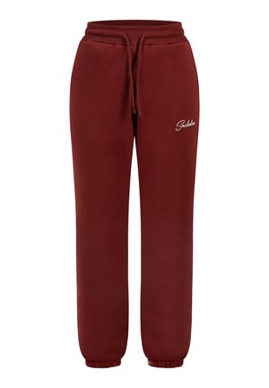Pantalones de chándal color burdeos con cintura elástica y cordón. Tobillos ajustados y un pequeño logo blanco en la pierna izquierda. Hechos de una tela suave.