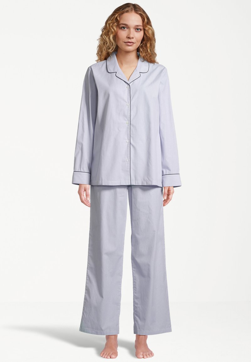 Vaatekokonaisuus sisältää vaaleansiniraidalliset puuvillapijamasetit, joissa on napitettava pitkähihaine paita ja leveälahkeiset housut, joissa on kaulus ja mustat reunukset.