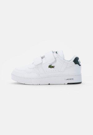 Witte sneaker met twee klittenbandsluitingen, rubberen zool en getextureerde stiknaad. Heeft een klein groen krokodillenlogo en een zwarte hakaccent.