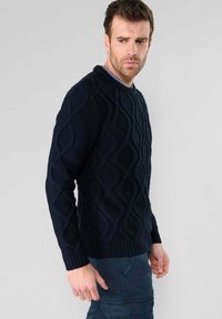 Marineblaue Strickjacke mit einem strukturierten, gewellten Zopfmuster, Rundhalsausschnitt und gerippten Bündchen. Eignet sich für legere Anlässe.