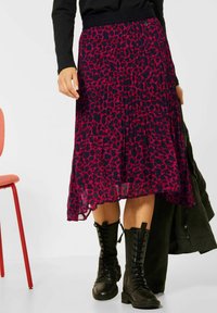Falda midi plisada en navy con un estampado de leopardo rosa. Llevada con botas negras con cordones, que cuentan con una textura suave y una cinturilla elástica.