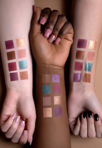 Drei Arme mit Nagellack zeigen Make-up-Proben auf verschiedenen Hauttönen. Verschiedene quadratische Farbproben umfassen Schimmer und Mattierungen in unterschiedlichen Farbtönen.