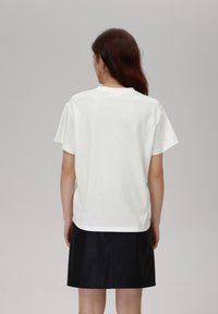 White cotton t-shirt with short sleeves and a round neckline, paired with a black leather mini skirt, smooth texture, simple design.