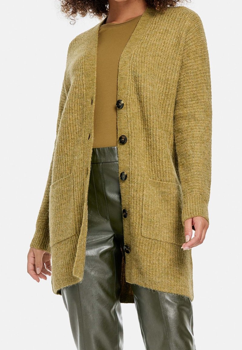 Olivově zelený pletený svetr s výstřihem do V, předními knoflíky a dvěma kapsami. Dlouhé rukávy s ribovanými manžetami. Texturovaná, měkká látka.