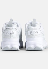 Scarpe bianche FILA con un design testurizzato, dettagli grigi, colli imbottiti e suola curva per il comfort, dotate di un anello per una facile calzata.