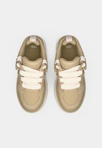 Μπεζ αθλητικά παπούτσια με λεία συνθετική επάνω επιφάνεια, παχύ λευκό πέλμα και κορδόνια από παστέλ ροζ σχοινί. Μίνιμαλ σχεδιασμός με επενδυμένο γιακά.