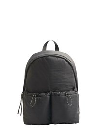 Sac à dos noir de forme arrondie, fabriqué en tissu texturé. Il dispose d'une poignée supérieure et de deux poches avant avec des fermetures à cordon.