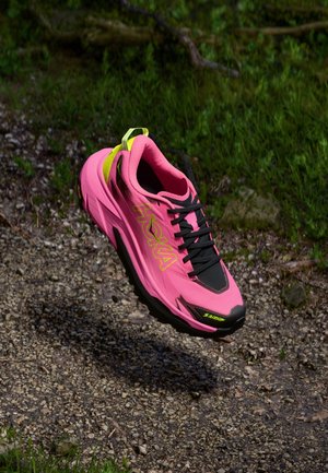 Chaussure de sport rose avec des accents noirs, tige en maille, semelle épaisse et marquage HOKA bien en vue. Comprend une languette au talon jaune et des lacets.