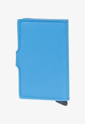 Cartera compacta de tela azul claro con costuras visibles y una pequeña pestaña negra en el borde inferior derecho.