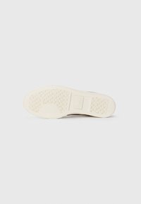 White rubber sneaker sole with textured pattern. Features include a logo on the side and a smooth, rounded shape.