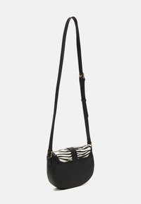 Sort skuldertaske med en buet silhuet, glat lædermateriale og en klap i zebrastribet stof med en sort rem.